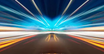 A vibrant, abstract image showing dynamic light trails and rays, creating a sense of speed and motion against a dark background.